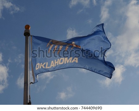 The flag of Oklahoma State waving in the skies on a bright sunny day
