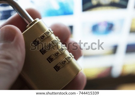 Padlock Passcode Concept with Laptop Computer in the Background. Safe Padlock in a Hand Closeup Photo.