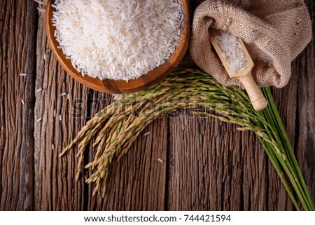 white rice (Thai Jasmine rice) in wooden bowl and unmilled rice on wooden background.