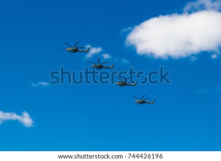 Flight of four military helicopters. Air parade. Air force day. Side view. Flight formation. Serene blue sky and white clouds.