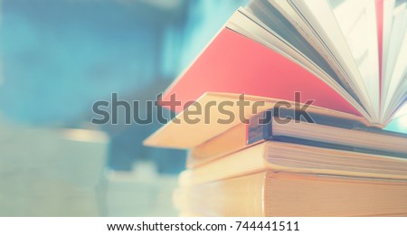 Open book on wood desk in the library room with blurred focus for background, education back to school concept, vintage color tone process