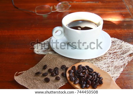 Hot black coffee with white cup on wooden floor is backdrop.