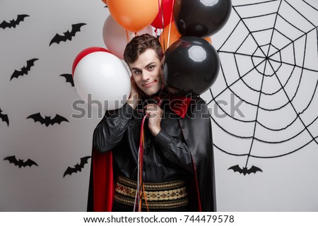 Vampire Halloween Concept - Portrait of handsome caucasian in Vampire halloween costume with colorful Balloon.