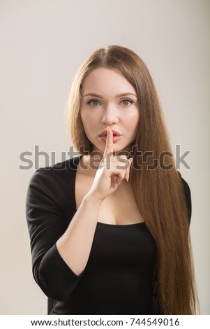 Cute girl doing silence gesture on studio background.