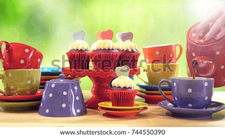 Colorful Mad Hatter style tea party with cupcakes and rainbow colored polka dot cups and saucers, with bokeh garden background and lens flare, pouring tea. 