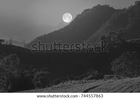 Black and white image of full moon over the mountain