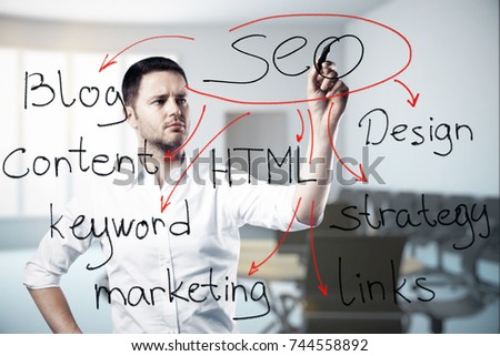 Attractive young european businessman drawing SEO sketch in blurry office interior. Content concept