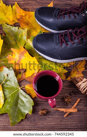 Hiking boots with autumn leaves on a wooden floor

