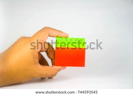 Hand holding Red and green plastic building blocks isolated on white background