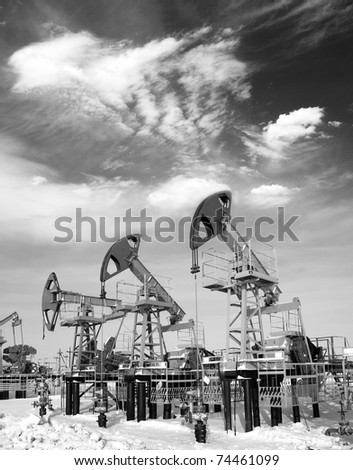 Oil and gas industry. Work of oil pump jack on a oil field. White clouds above oil field. Black and white photo