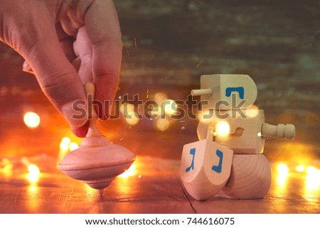 Image of jewish holiday Hanukkah with wooden dreidels colection (spinning top) and gold garland lights on the table