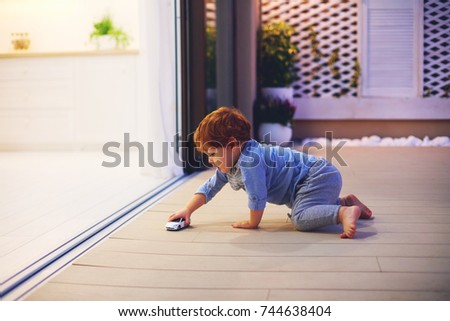 cute toddler baby boy playing with toy car at the patio with open space kitchen and sliding doors
