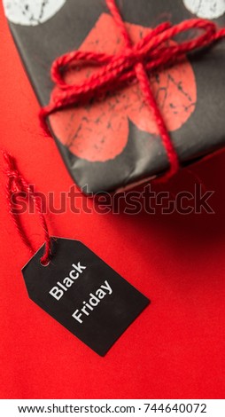 Gift box and black 'Black Friday' tag on red background