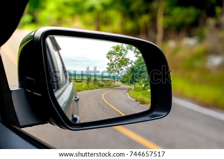Landscape in the sideview mirror of a car , on road countryside. Royalty-Free Stock Photo #744657517