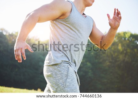 Fitness man athlete jogging in the nature during sunset. Person running working out living an active lifestyle training cardio in summer in sportswear and shoes