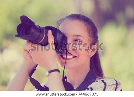 Portrait of positive young female with photocamera at park