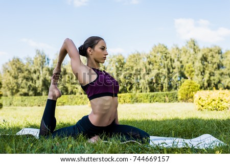 athletic woman in penguin pose practicing yoga outdoors