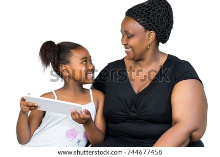Close up portrait of little african girl and mother having fun together with digital tablet isolated on white background.Mother and daughter looking at each other.