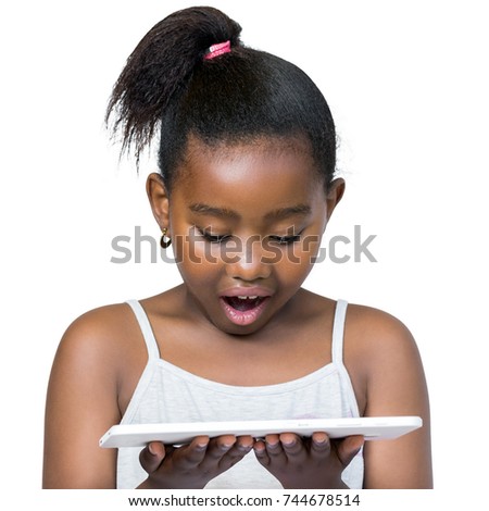 Close up portrait of cute little african girl with ponytail looking down at digital tablet.Kid with surprised facial expression Isolated on white background.