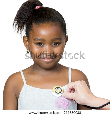 Close up portrait of cute little african girl having heartbeat taken.Hand positioning stethoscope against chest.Isolated on white background.
