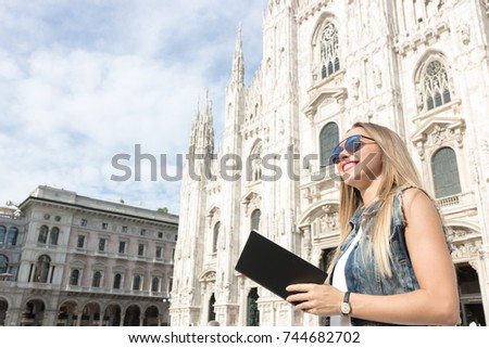 Pretty teenager tourist with her travel guide visiting the city. Copy space on the guide cover. Photo taken in Milan, Italy.