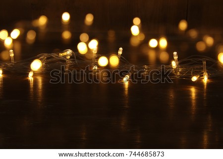 Christmas warm gold garland lights on black wooden background.