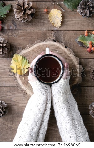 top view, woman holding cup of hot tea on wooden table, close-up photo of hands in warm sweater with mug,Warm soft cozy image. Details.