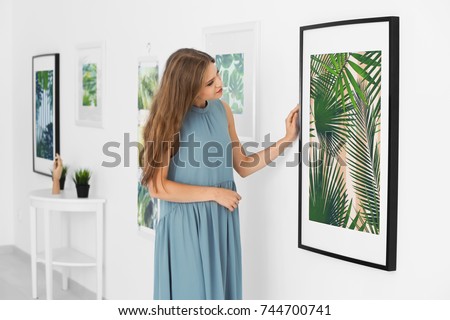 Young woman looking at picture of tropical foliage in art gallery