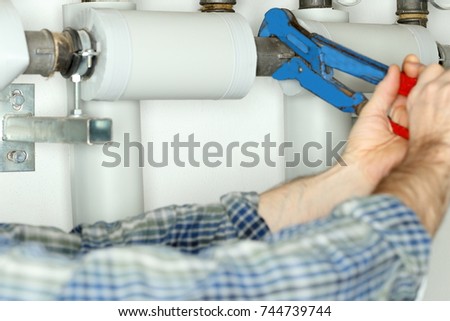 worker with gripper in hand is repairing a pipe