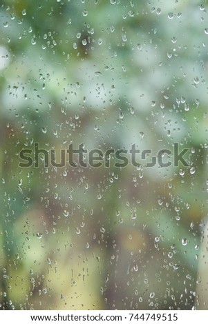 Raindrops fall on the window glass