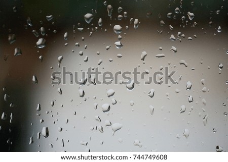 Raindrops fall on the window glass