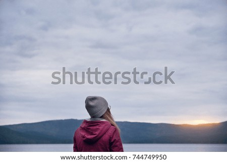 Rear view of hipster woman looking at sunset over the mountains