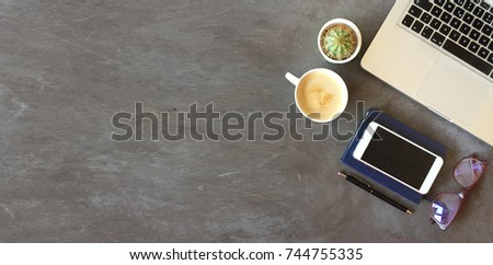 Top view of office desk on textured dark gray background 