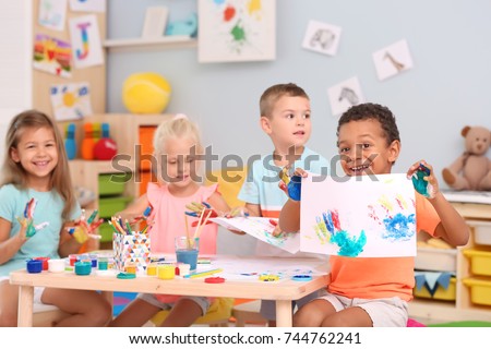 Cute children painting with their palms at table indoor Royalty-Free Stock Photo #744762241