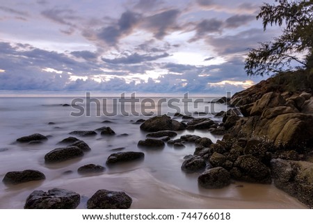 A beautiful sunset seascape with motion of waves at Naithon Beach, one of famous tourist beaches in Phuket island, Thailand. Soft focus taken with slow shutter speed.