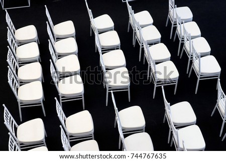 row of empty white chair on black carpet in hall room  top view
