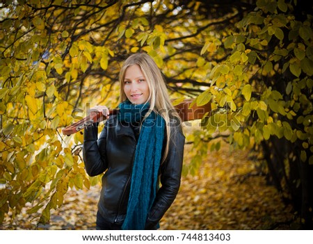 Beautiful long-haired girl with a guitar. Autumn portrait.