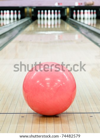 Pink sphere ball standing on bowling lane before strike