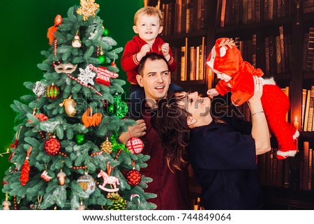Parents pose with their little sons before a Christmas tree