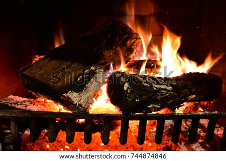 A close up image of a lit wood fire in a fireplace.