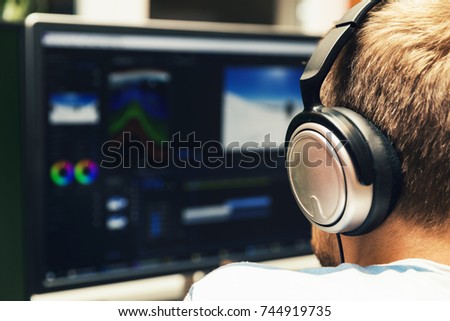 man doing video editing on computer with headphones on