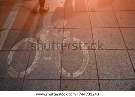Bicycle paths on the concrete floor and shadows of people walking.