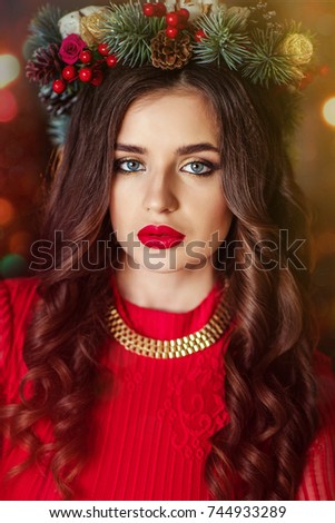 beautiful girl in a red dress, in a wreath of fir branches on her head, meets the new year