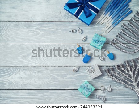 Jewish holiday Hanukkah background with menorah, gift box and dreidel over wooden table. View from above. Flat lay