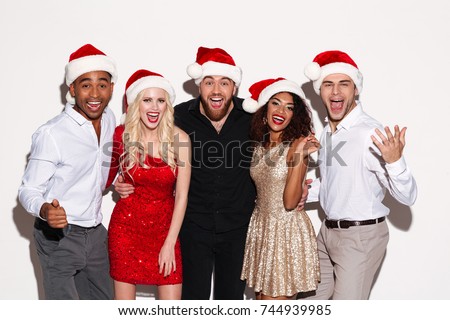 Image of screaming cheerful group of friends wearing christmas hats standing over white isolated background. Looking camera.