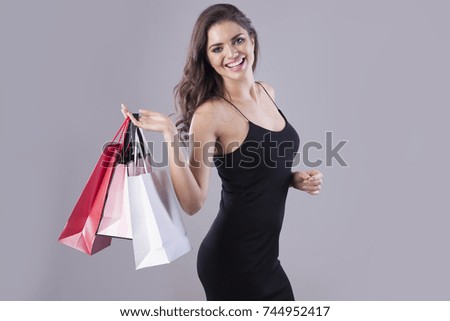 Elegant woman with shopping bags isolated on grey background.