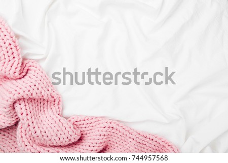 Bedding with a pink knitted plaid. Copy space. Flat lay, top view Royalty-Free Stock Photo #744957568