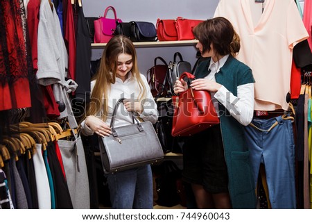 Smiling young woman with shopping bags over mall background. Happy girl buy clothes with discounts.