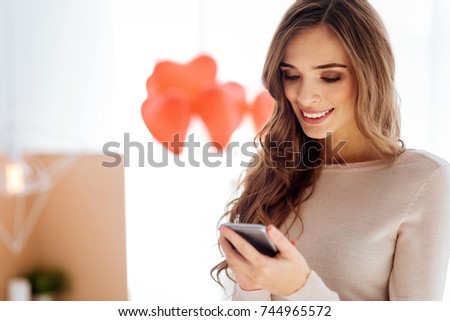 Smiling girl using smartphone indoors
