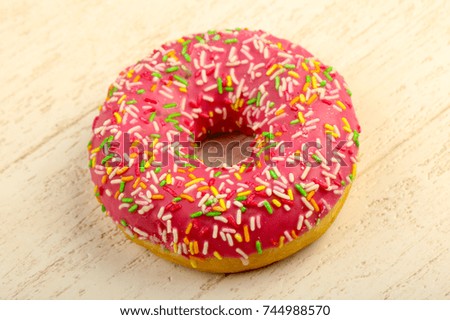 Pink Sweet iced donut over wooden background